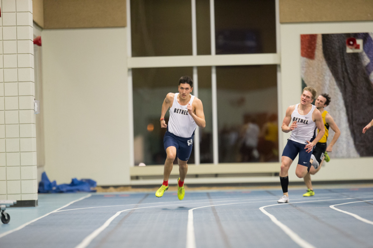 Freshman Shawn Monroe surges toward the finish line at Macalester College Jan. 20. In one week he would finish a race and win his heat with only one shoe. | PHOTO BY NATHAN KLOK