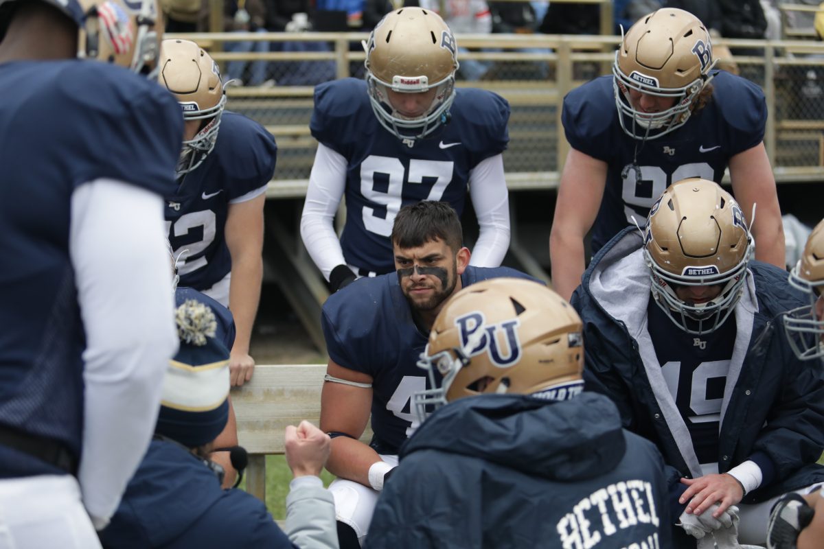 Bethel University football players huddle on the sideline during a game against Hamline University Nov. 2. | Photo by Jhenna Becker