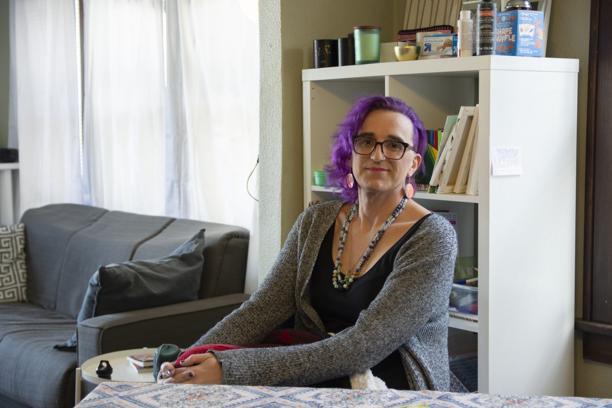 Leigh Finke poses in her at-home work space. The room is decorated with colorful artworks made by Finke and her children. | Photo by Emma Gottschalk