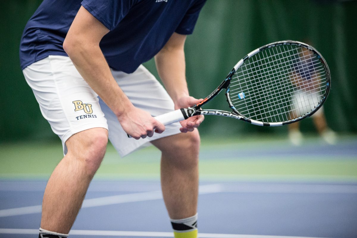 A tennis player squats into read position, anticipating the placement and speed of the ball just before the opponent serves. Photo by Nathan Klok. 