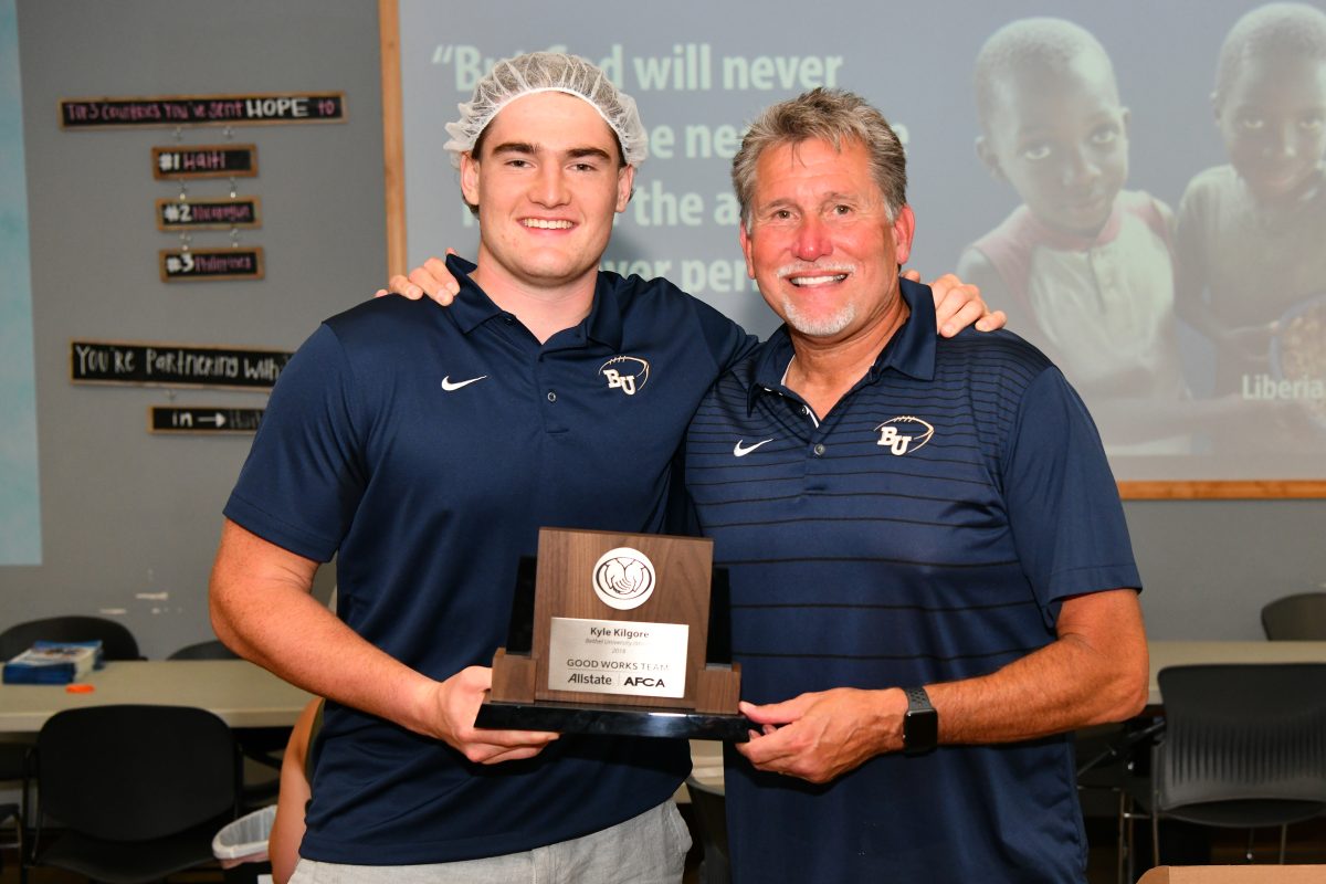 Kyle+Kilgore+displays+his+Allstate+Good+Works+Team+trophy+alongside+Bethel+head+football+coach+Steve+Johnson.+Allstate+surprised+Kilgore+and+his+teammates+at+a+local+Feed+My+Starving+Children+packing+center+to+award+the+trophy.+%7C+Photo+submitted+by+Allstate