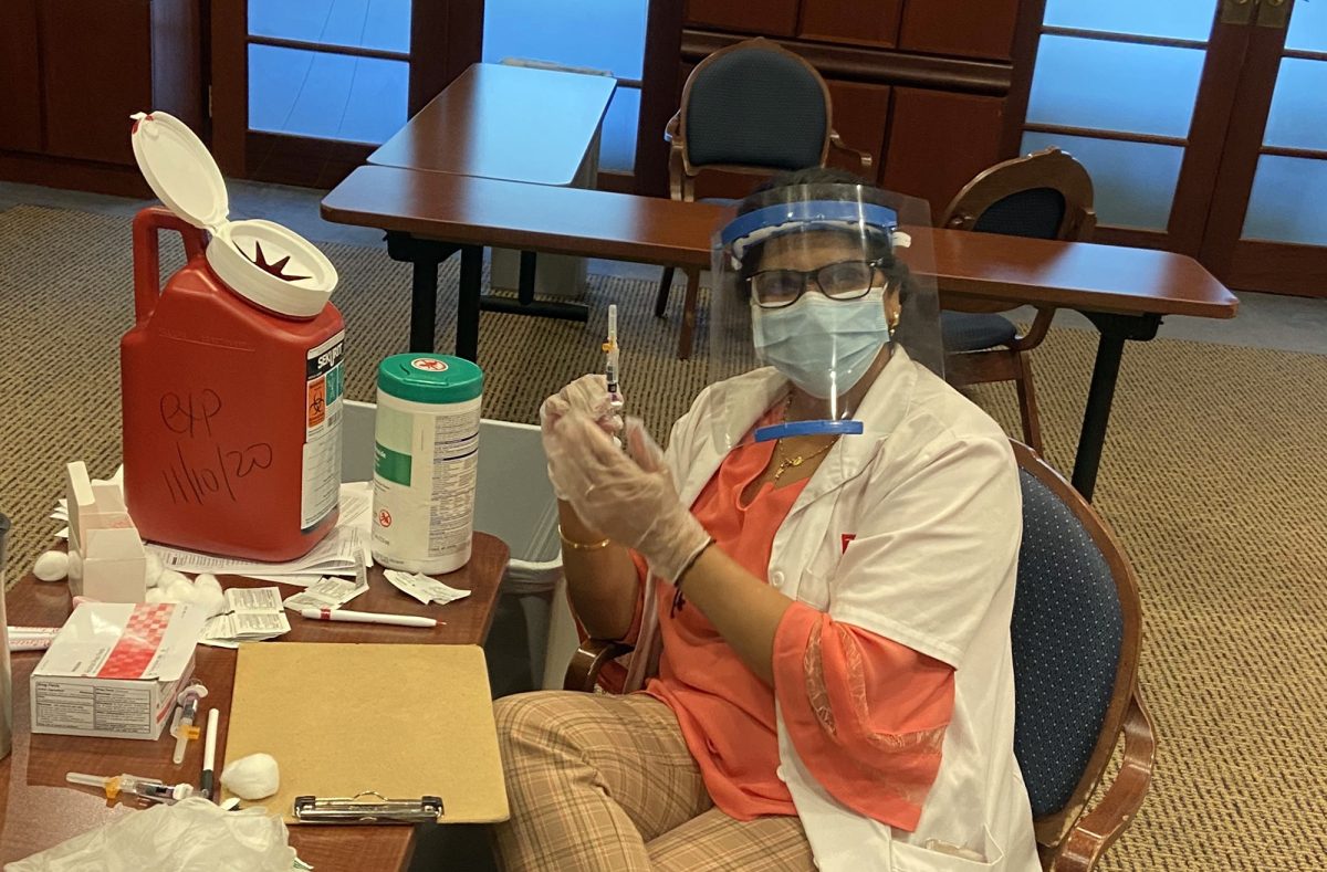 Pharmacist Kavitha Thomas prepares to give a flue shot to the next Bethel patient Tuesday in the Eastlund Room.