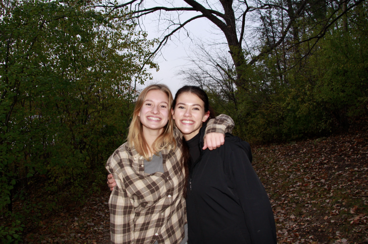 Seniors Cady Peterson and Vivian Marchan pose near the Lakeside Plot where they spent many hours over the last two years collecting data. Both students frequently wore chest-high waders and crawled under branches and shrubbery to count buckthorn stems. “I'm really thankful that I had someone as amazing as Cady to do research with,” Marchan said.