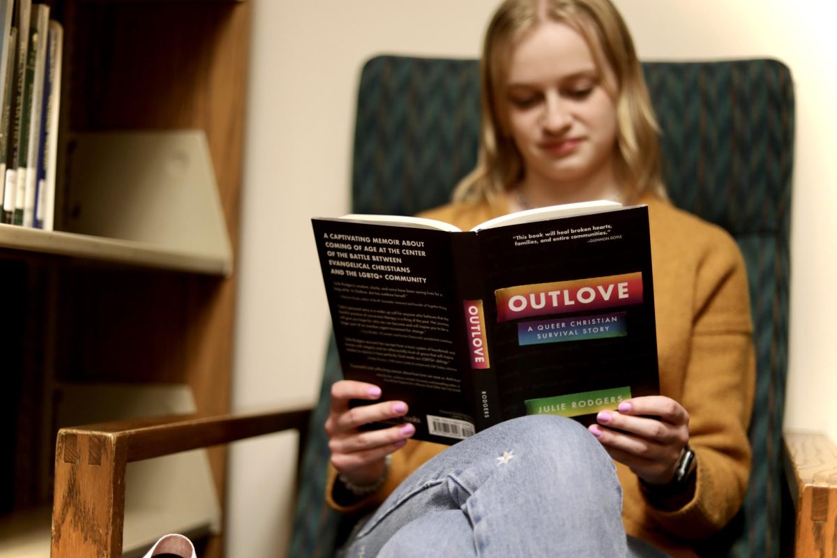 Junior Sarah Niehnaus reads one of her favorite books, “Outlove: A Queer Christian Survival Story” by Julie Rodgers in the library April 18.