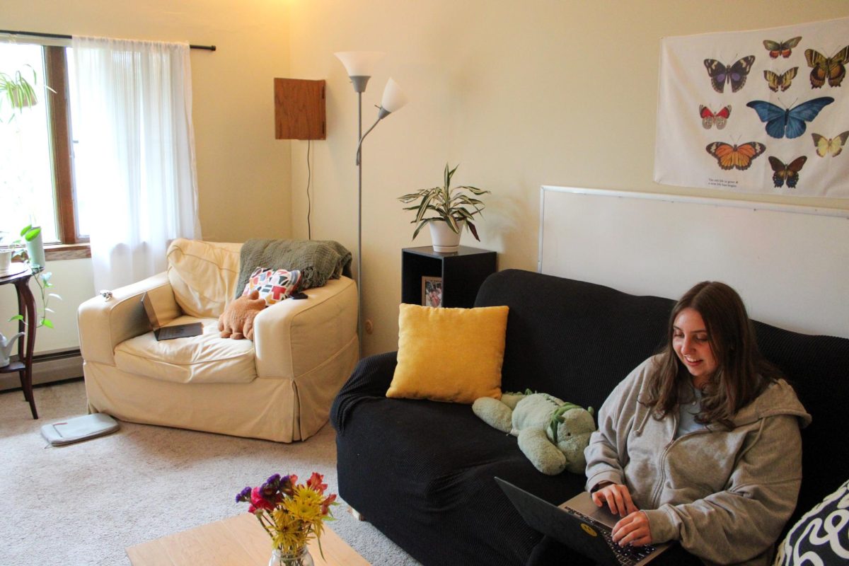Emma Lovell sits in her living room at her North Village apartment. Lovell talks to her roommate before heading to the design lab to lead a meeting for her Welcome Week committee.