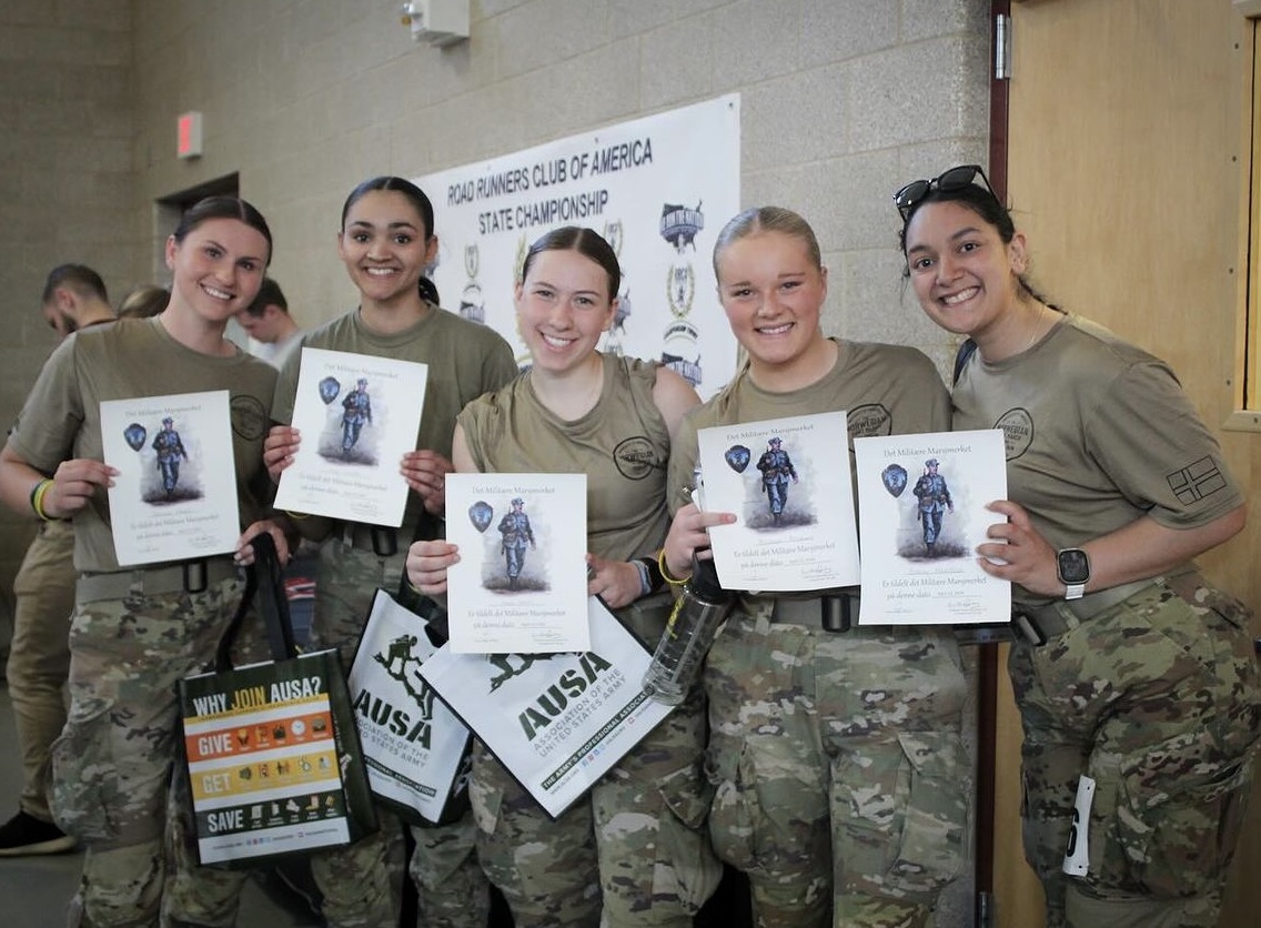 Cadets, Ashlyn Erickson and Paige Caouette, smile with fellow cadets after completing the Norwegian foot march. The training event included marching 19.2 miles with equipment strapped to their backs. The soldiers are glad the event is over, but ready for the next one. “It takes a lot sometimes or sometimes it can be easy,” Erickson said. | Photo submitted by Ashlyn Erickson.