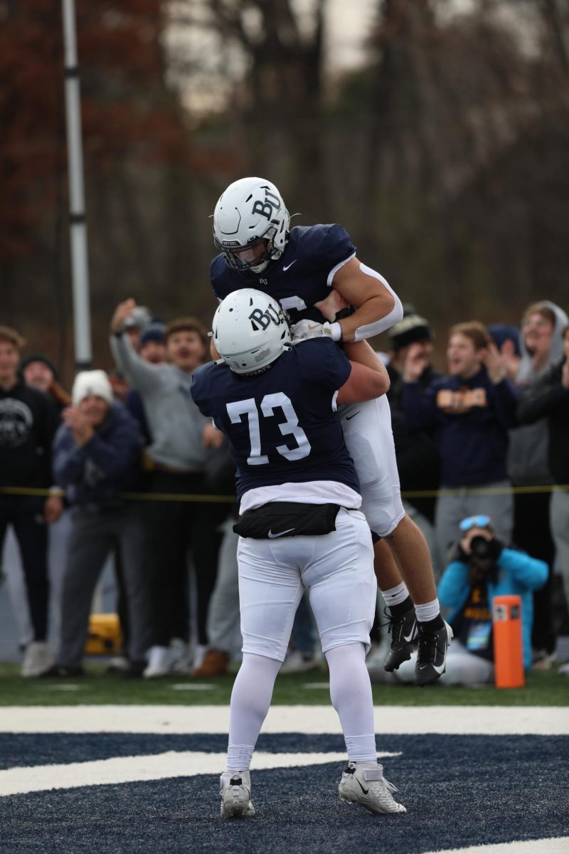 Bethel center Jaeger Ash lifts running back Aaron Ellingson in celebration following a touchdown Saturday. Ellingson scored three of Bethel’s four touchdowns in the NCAA playoff victory and added 115 yards from scrimmage. 