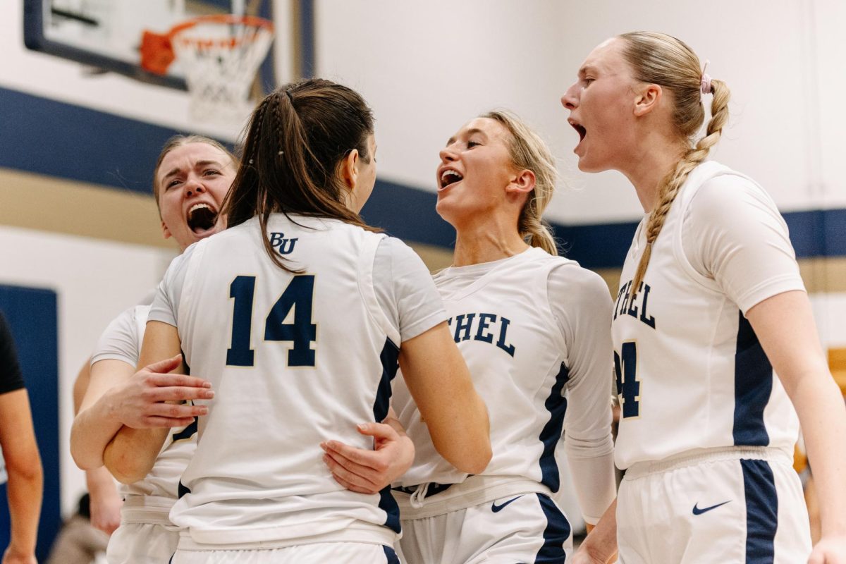 Fifth-year guard Anna Garfield (14) celebrates an and-one three-pointer with team captain Rosie Penke (left), team captain Colette “Coco” Duininck (center) and fifth-year forward Lydia Hay (right). This season’s Bethel women’s basketball team has centered itself around its cohesion – a large contributor to the success of the team. “We just hype each other up so much,” junior Rosie Penke said. “Which is really fun, even if it's a joke. We're just cheering for each other so much.” 