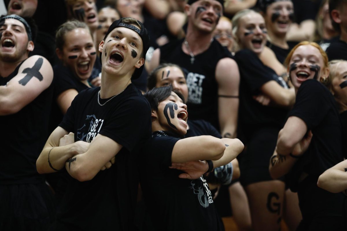 Two Getsch Hall residents sing back-to-back during Getsch's cheer Oct. 13, 2025, in the Robertson Center gym at Bethel University.